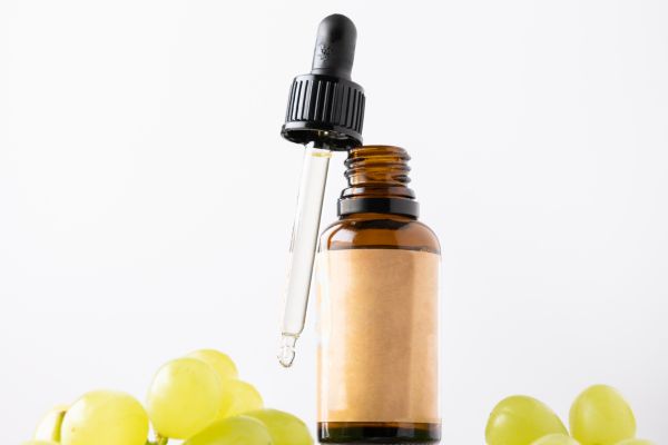 Essentiele olie in fles met druppel druiven