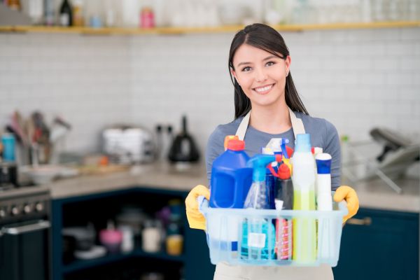 Vrouw blij met glimlach met allemaal verschillende schoonmaak spullen