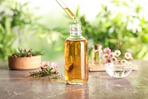 Fles met een olie erin en op achtergrond de planten en bloemen waarvan het is gemaakt
