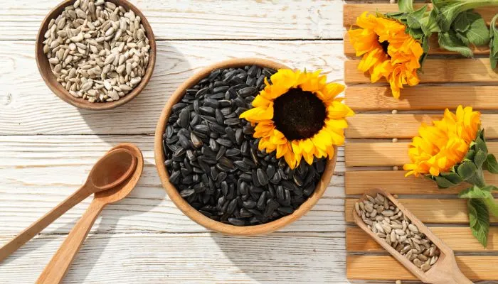 Zwarte-zaad-olie-met-houten-lepel-en-gele-bloemen-op-houten-tafel Zwarte zaad olie met houten lepel en gele bloemen op houten tafel